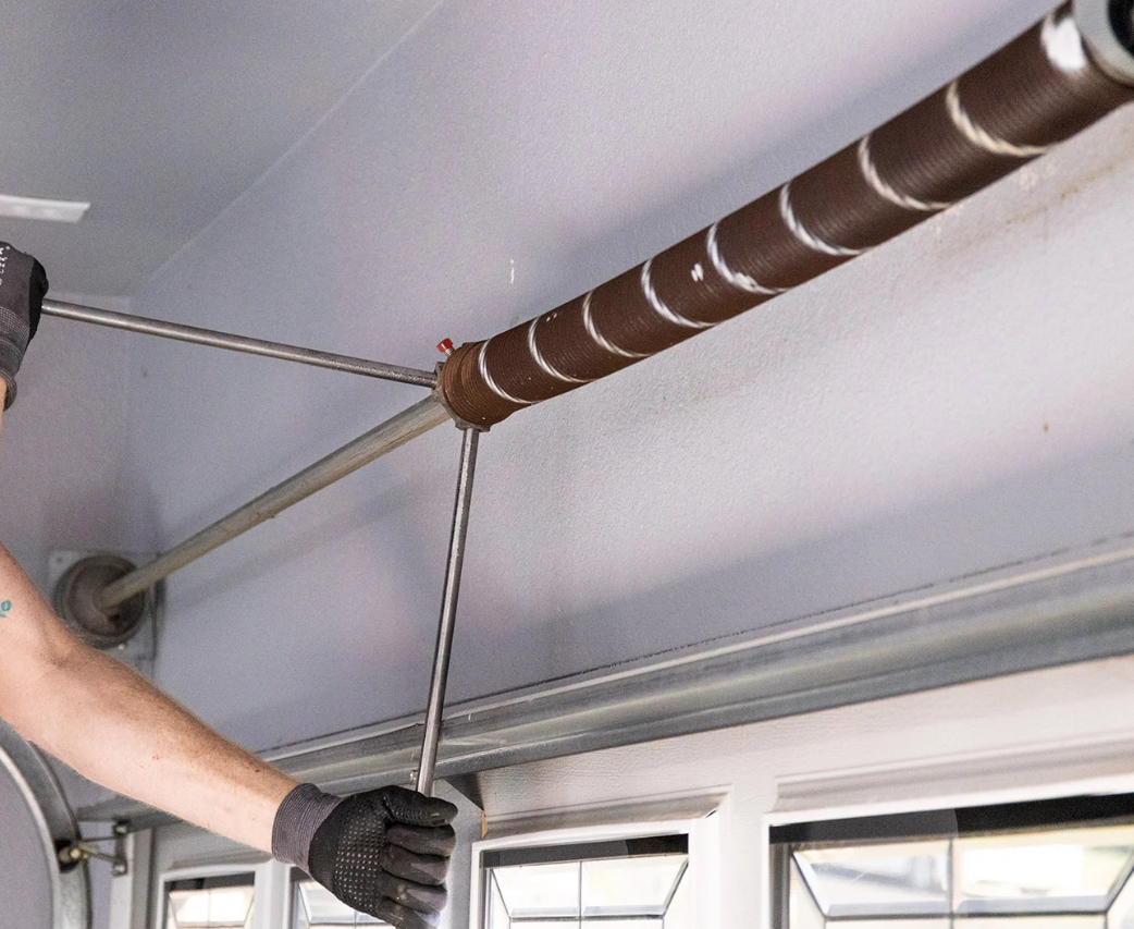 a professional technician performing garage door spring repair, demonstrating expertise and safety with specialized tools in Fort Pierce, FL, emphasizing reliable and efficient service by Garage Door Repair Services Fort Pierce FL."